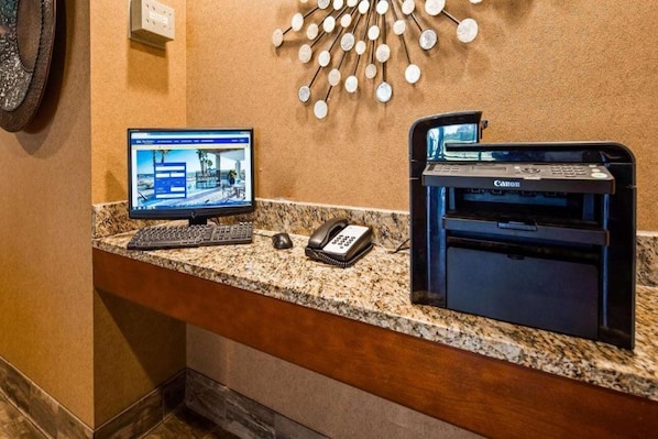 Un mostrador de recepción de hotel con una computadora de escritorio, una impresora Canon y un teléfono.