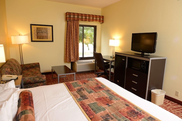 A hotel room with a bed, a desk, a television, a chair, a lamp, and a window with curtains. - Robinsonville Tunica Resorts (Robinsonville)
