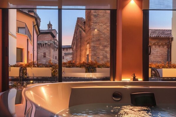 Un jacuzzi con vistas a edificios históricos y un balcón.