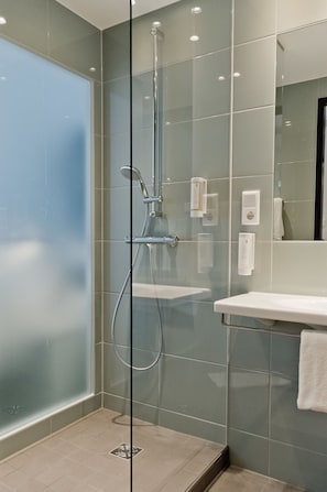 Ein modernes Badezimmer mit Duschkabine aus Glas, einem weißen Waschbecken und einem Spiegel.