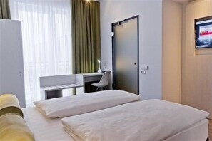 A hotel room with a bed, a desk, and a chair. - Premier Inn München City West (Munich)