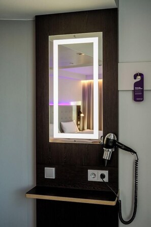 Ein Hotelzimmer mit Spiegel, Fön und Telefon auf einer Holzauslage.