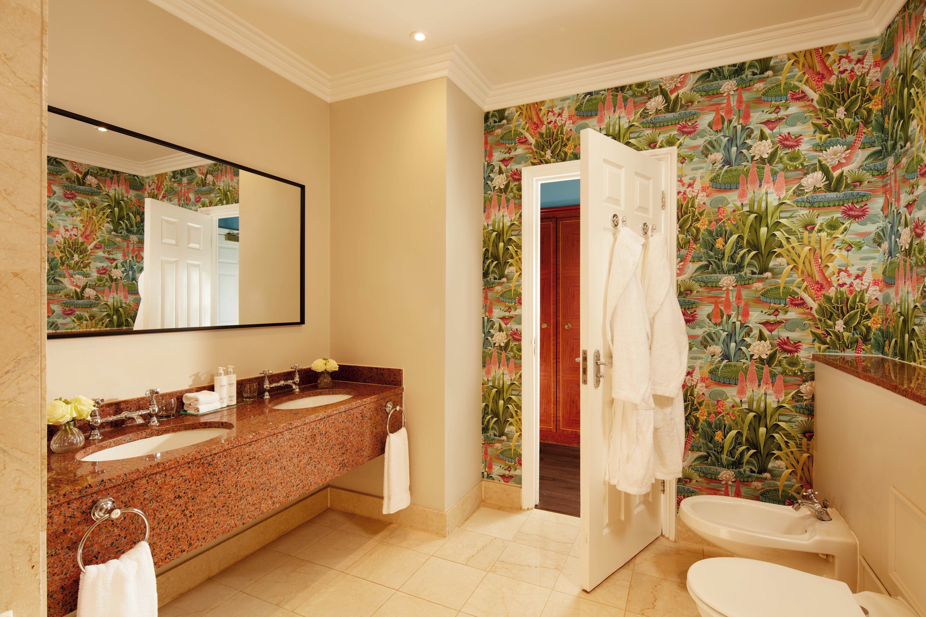 A bathroom with a marble vanity, a large mirror, a sink, a toilet, and a shower.