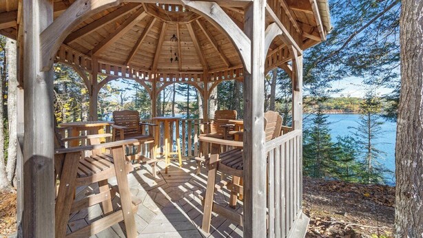 Ein hölzernes Gazebo mit Blick auf einen See und Bäume.