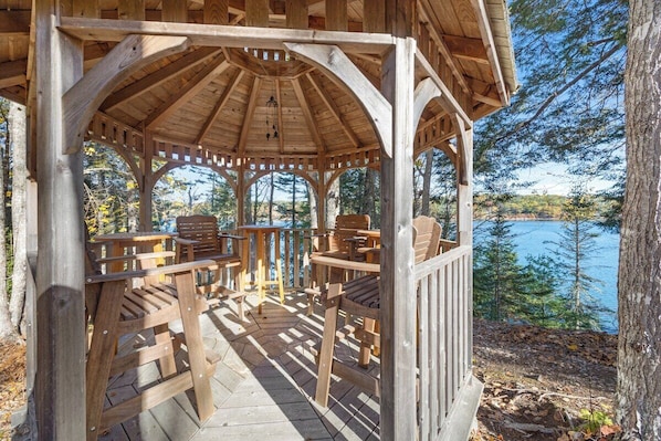 Ein hölzernes Gazebo mit Blick auf einen See und Bäume.