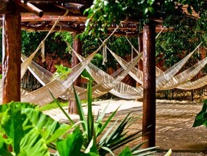 A hammock under a wooden pergola with greenery in the background. - Misne Hacienda (Mérida)