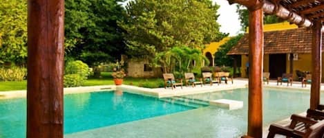 A pool area with wooden chairs and a pergola structure.