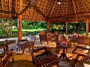 An outdoor seating area with wooden furniture and a thatched roof. - Misne Hacienda (Mérida)