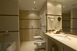 Un baño con bañera, inodoro, bidé, lavamanos y espejo.