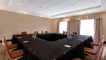 Un salón de conferencias con una mesa larga, sillas e iluminación empotrada en el techo.