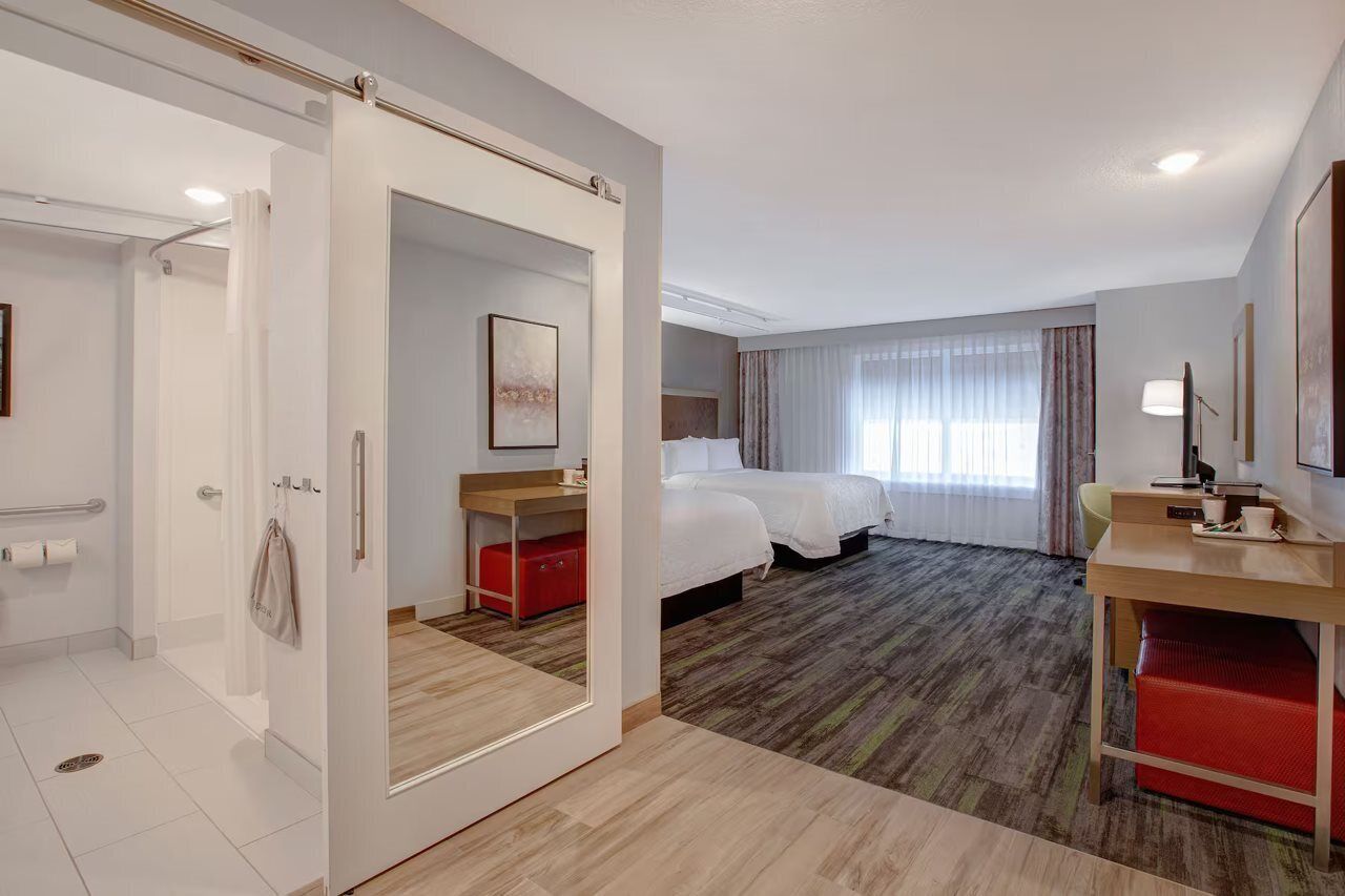 Une chambre d’hôtel comprenant un lit, un bureau, une chaise, un miroir et un espace douche.