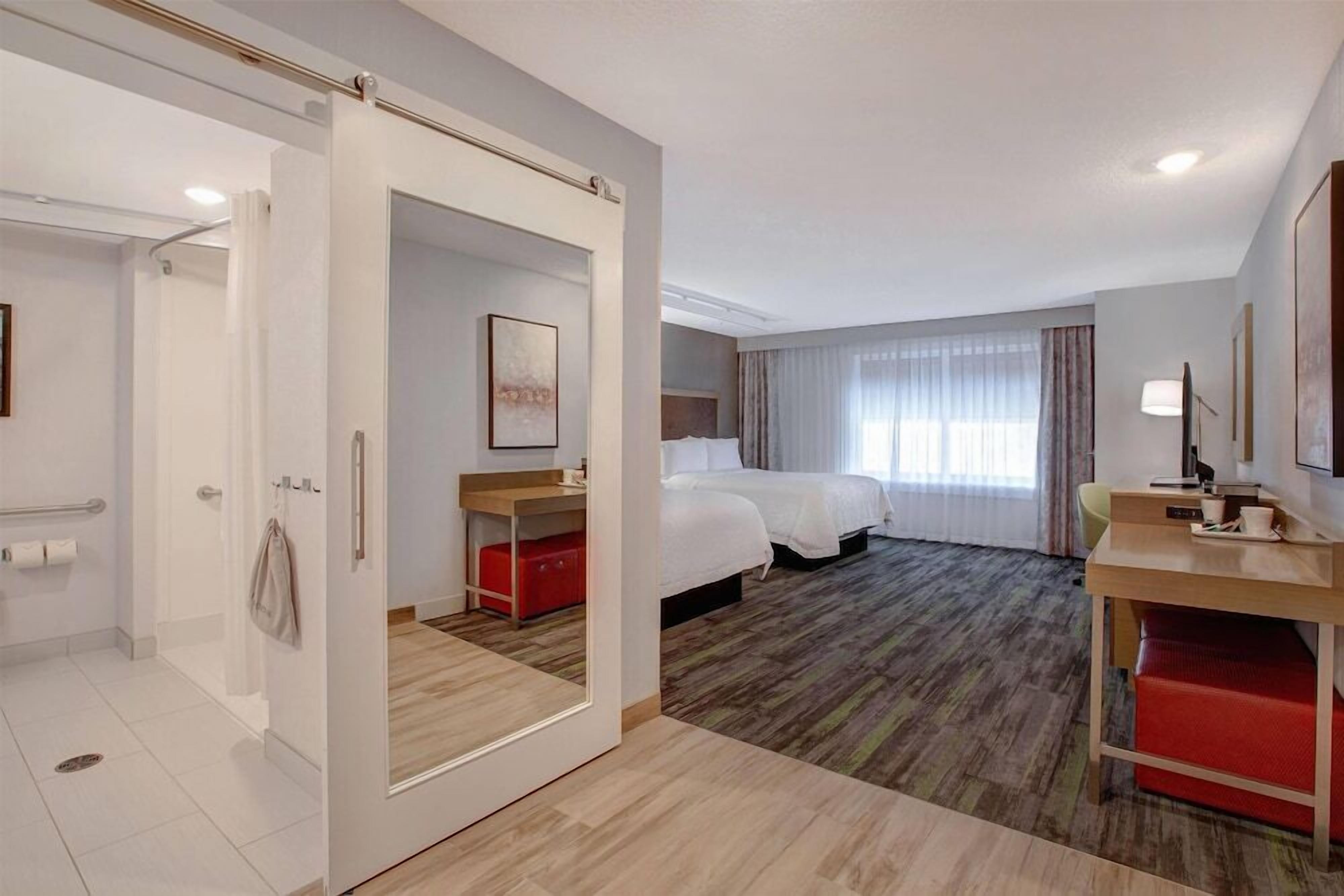 A hotel room with a bed, bedside table, and a desk with a chair.