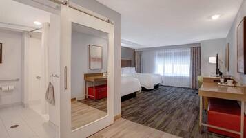 A hotel room with a bed, bedside table, and a desk with a chair.