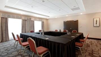 A conference room with a long table, chairs, and a projector screen.