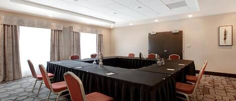 Une salle de conférence équipée d’une longue table, de chaises et d’un écran de projection.