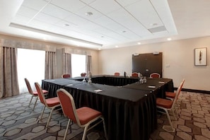 A conference room with a long table, chairs, and a projector screen.