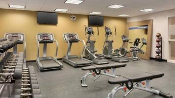 A gym with treadmills, elliptical machines, and free weights.