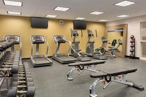 Un gimnasio con cintas de correr, elípticas y pesas sueltas.