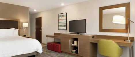 A hotel room with a bed, desk, television, and a mirror.