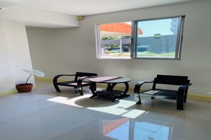 A room with a large window, a potted plant, two chairs, and a small table. - ECO Hostel (Hua Hin)