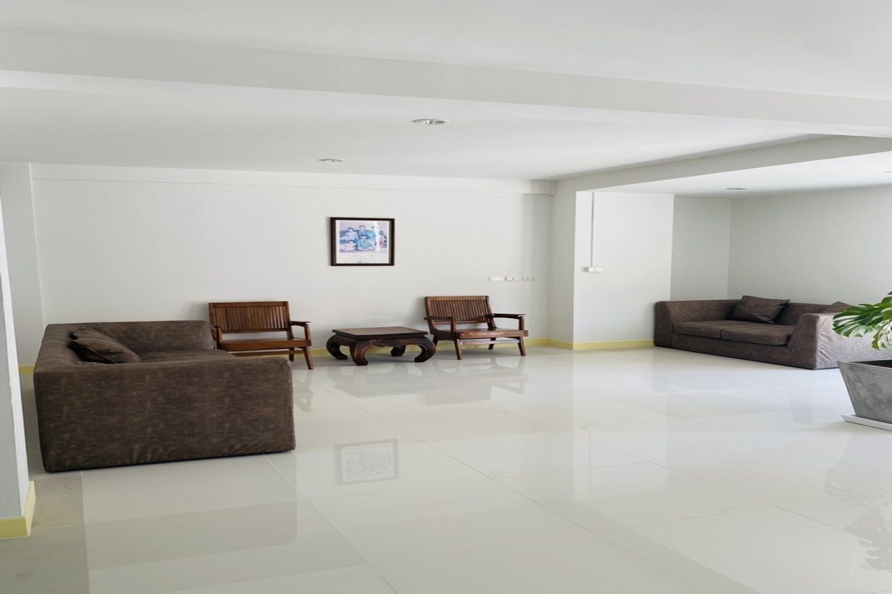 Ein geräumiges Wohnzimmer mit einem großen Sofa, zwei Holzstühlen, einem Couchtisch und einer Topfpflanze.