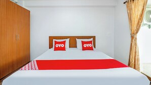 A hotel room with a bed, a wooden wardrobe, and a window with curtains. - Eco Hostel (Hua Hin)