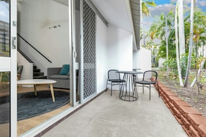A modern patio with a table and chairs, a sliding glass door, and a view of palm trees. - Travelodge Resort Darwin (Darwin)