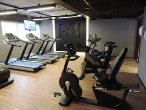 A gym with treadmills, stationary bikes, and an elliptical machine.