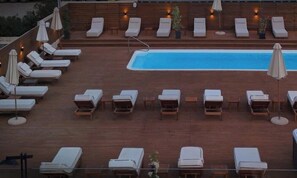 Uma área de piscina no terraço com espreguiçadeiras e guarda-sóis.