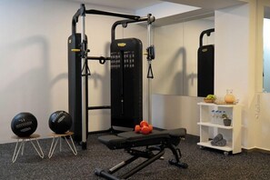A gym with a squat rack, bench, and dumbbells. - Villaggio Boutique Hotel Hersonissos - Adults Only (Hersonissos)