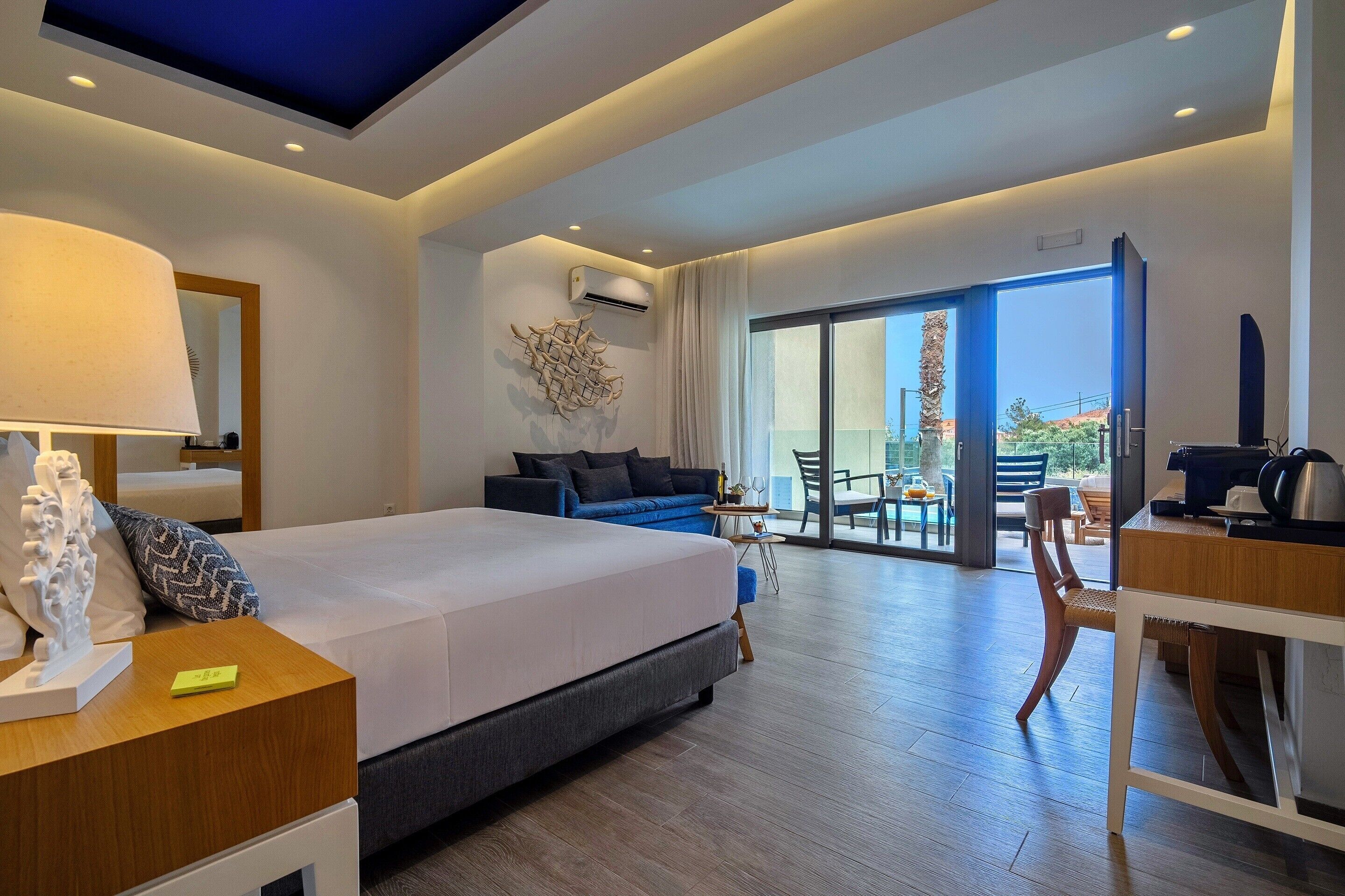 Habitación de hotel moderna con una cama grande, un escritorio, una silla y vistas al exterior.