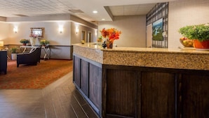 Zona de recepción de un hotel con mostrador, asientos y plantas decorativas.