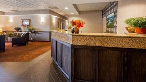 Ein Hotel-Empfangsbereich mit Theke, Sitzgelegenheiten und Zierpflanzen.