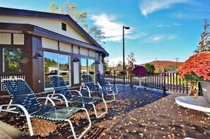 Ein Gebäude mit überdachter Terrasse, Sitzgelegenheiten im Freien und einer Zierpflanze.