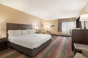 Habitación de hotel con una cama grande, dos mesitas de noche, un escritorio, una silla y una lámpara de escritorio.