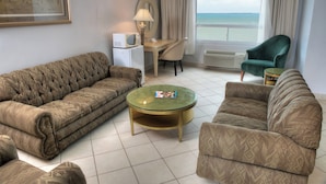 A living room with a sofa, armchair, and a small table with a lamp. - Ramada by Wyndham Princess Belize City (Belize City)