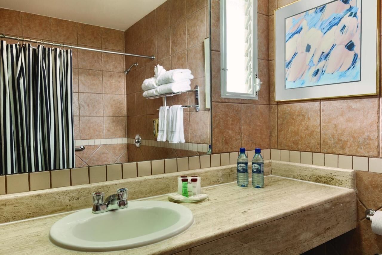 A bathroom with a sink, towel rack, and a framed abstract painting.