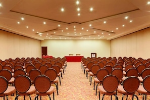Una sala de conferències amb files de cadires orientades cap a un escenari que té un púlpit i dues taules.