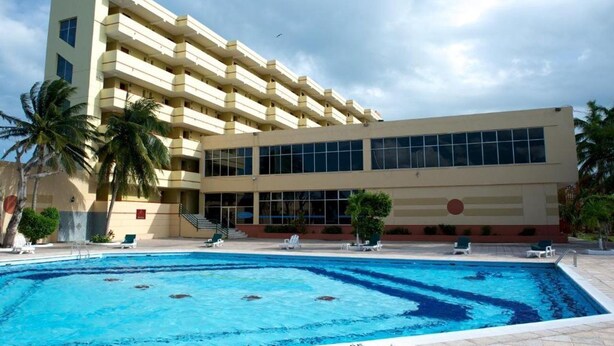 A hotel with a swimming pool, multiple balconies, and a modern architectural design. - Ramada by Wyndham Princess Belize City (Belize City)
