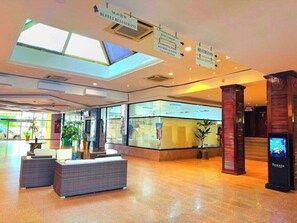 Um saguão de hotel com assentos, um restaurante em estilo buffet, salas de conferência, um centro de fitness e uma piscina.