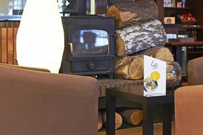 A cozy interior with a wood-burning stove, stacked logs, and a menu board. - Campanile Washington Newcastle-upon-tyne (Washington)