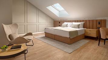 Un dormitorio con tragaluz, una cama, una mesita de noche, una silla y una pequeña mesa con un cuenco de fruta.