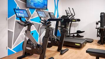 Un gimnasio con bicicletas estáticas, una cinta de correr y una máquina de pesas.