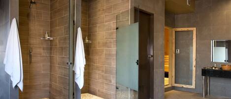 A modern bathroom with a glass-enclosed shower, a vanity with a mirror, and a tiled floor.