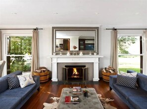 A living room with a fireplace, two sofas, a coffee table, and a large mirror above the fireplace. - L Avenir Country Lodge (Stellenbosch)