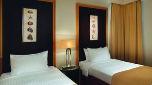 A hotel room with two beds, a nightstand with a lamp, and artwork on the walls. - Movenpick Resort Al Nawras Jeddah (Jeddah)