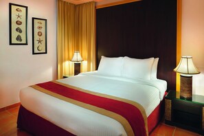 A hotel room with a large bed, two bedside tables, a red and gold bedspread, and framed pictures on the wall. - Movenpick Resort Al Nawras Jeddah (Jeddah)