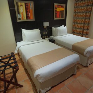 Habitación de hotel con dos camas, una mesita de noche, una lámpara y obras de arte en la pared.