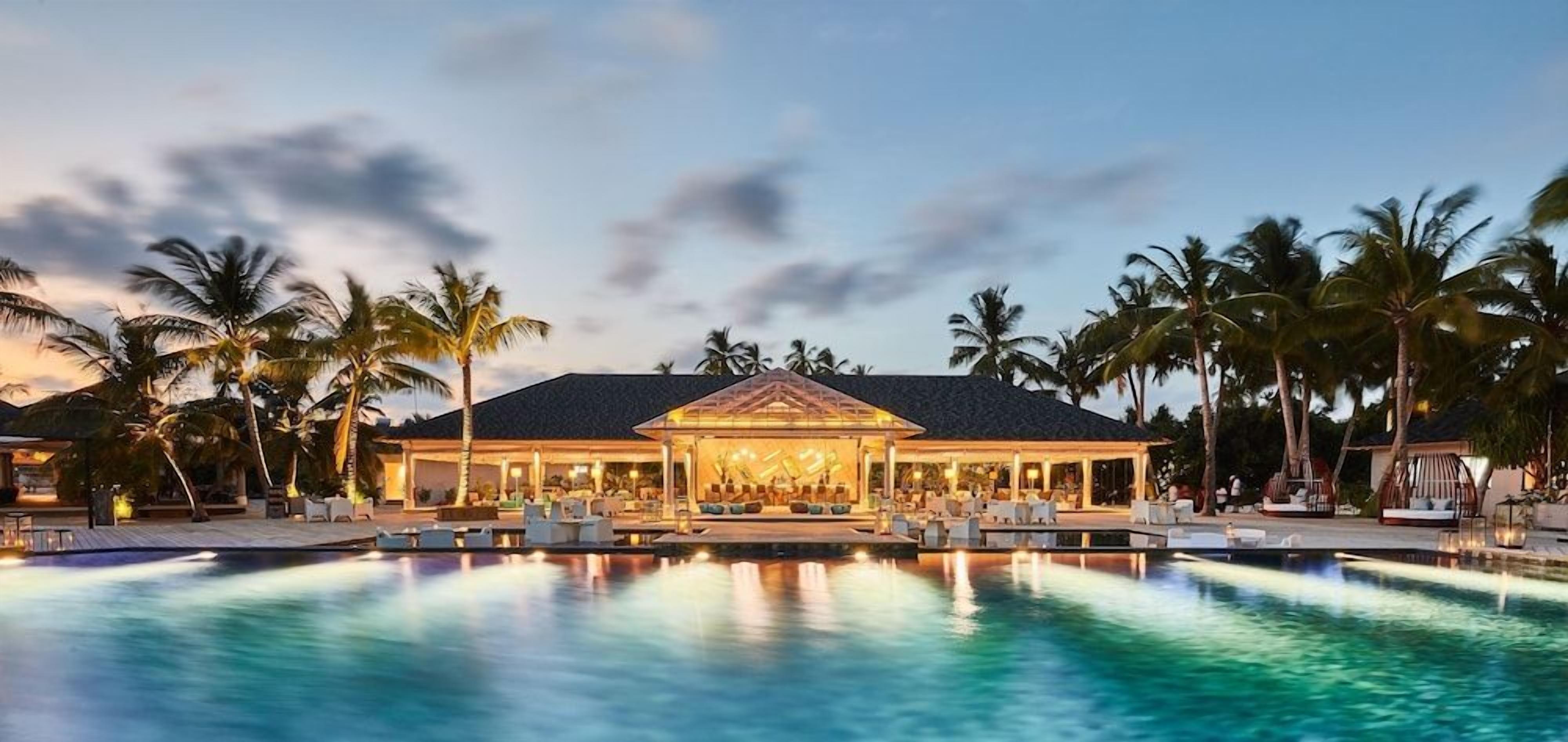 A resort with a large pool, palm trees, and a building with a covered area.