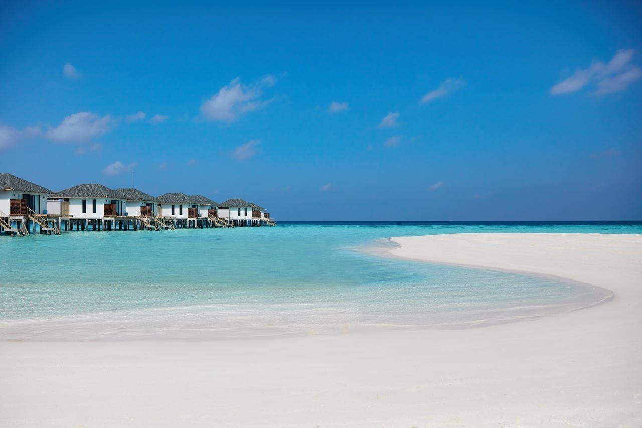 Overwater bungalows with a clear view of the turquoise sea and white sand beach.